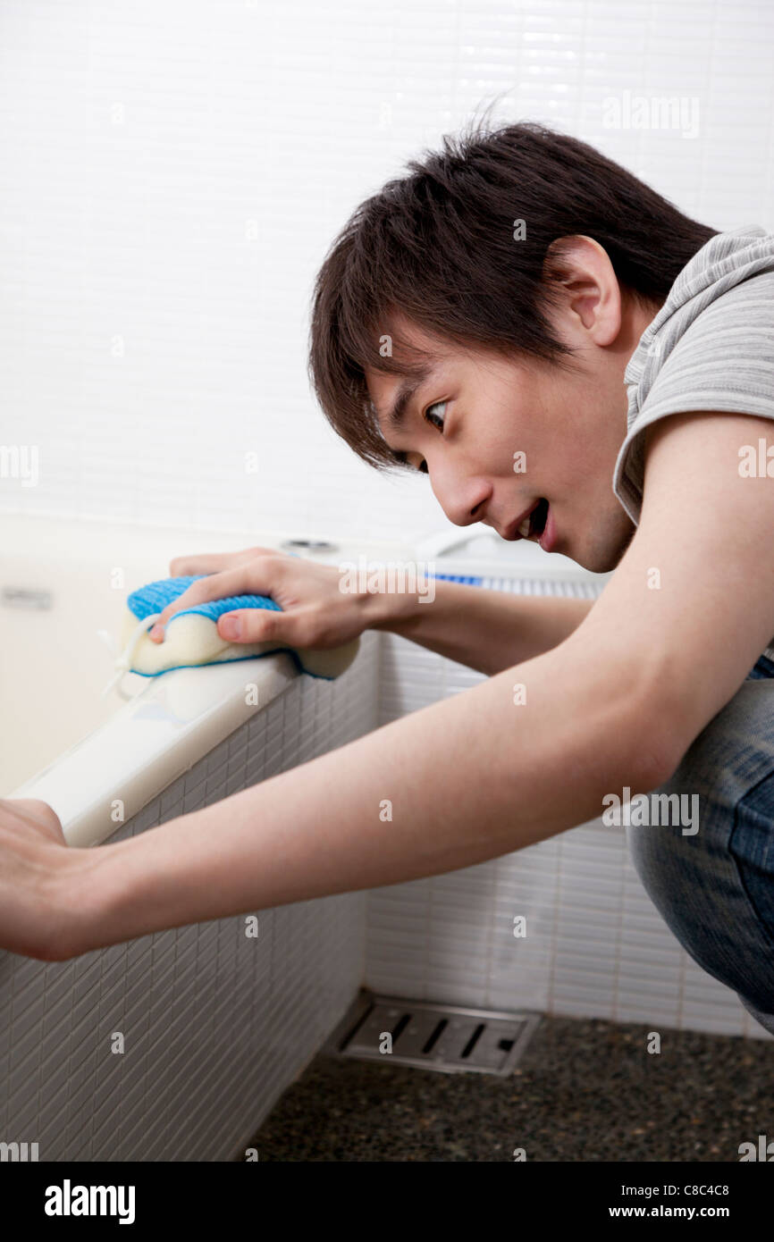 Young man scrubbing bathtub Stock Photo Alamy