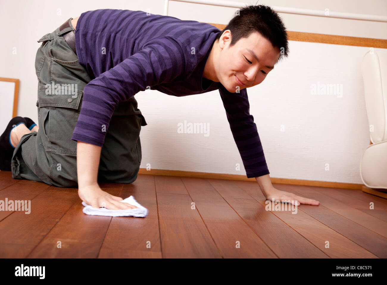 Young man on hands and knees swabbing floor with dust cloth Stock Photo Alamy