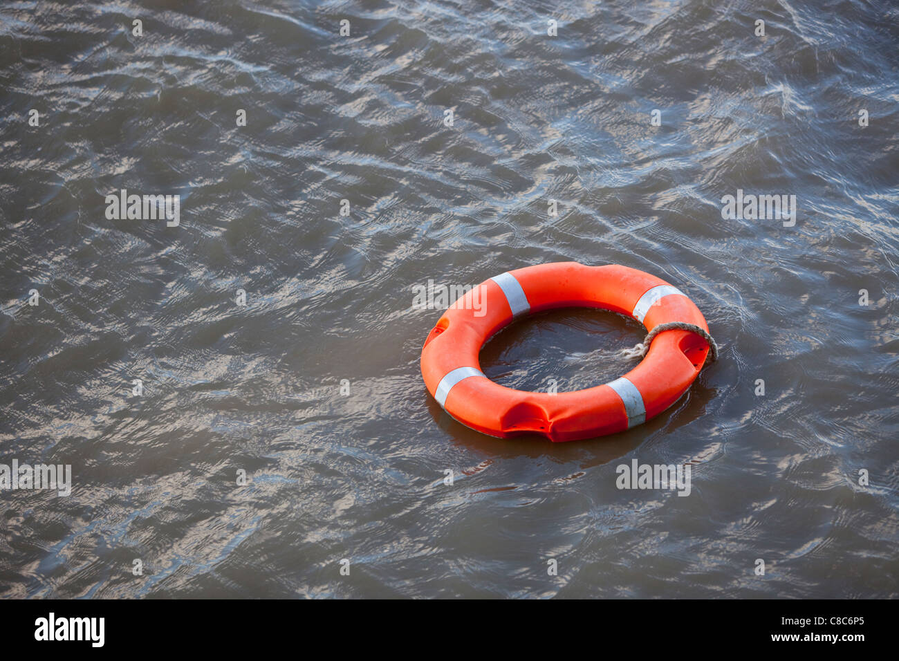 Orange life saver ring floating on River Thames, London, England, UK. Stock Photo