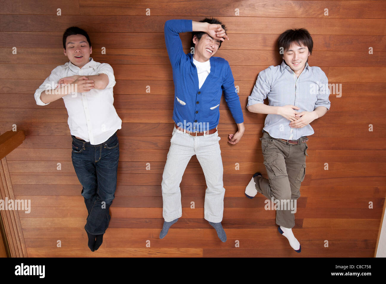 Three men relaxing on hardwood floor Stock Photo