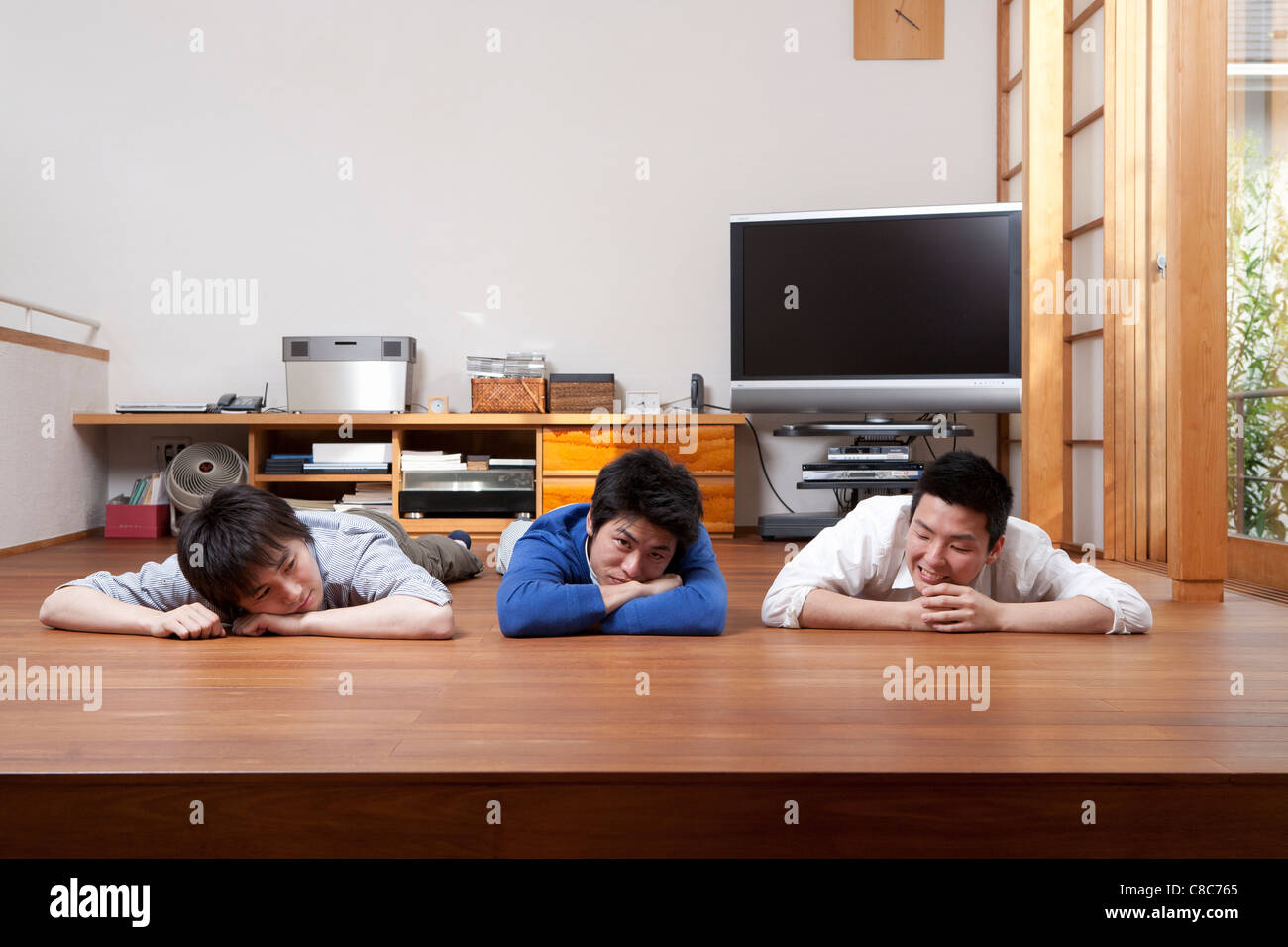 Three men relaxing on hardwood floor Stock Photo