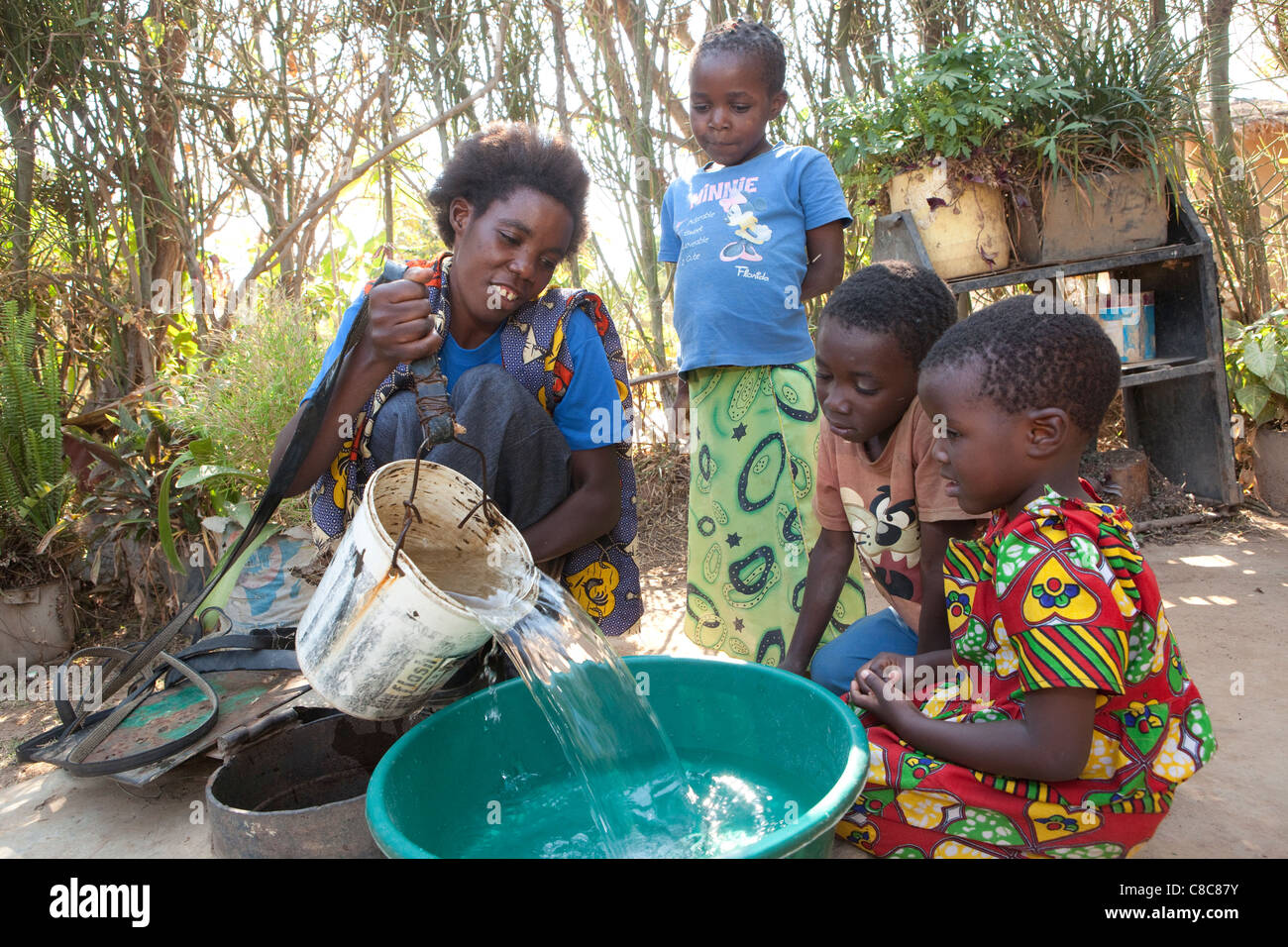 A woman and her children draw water from a well in Mongu, Zambia, Southern Africa. Stock Photo