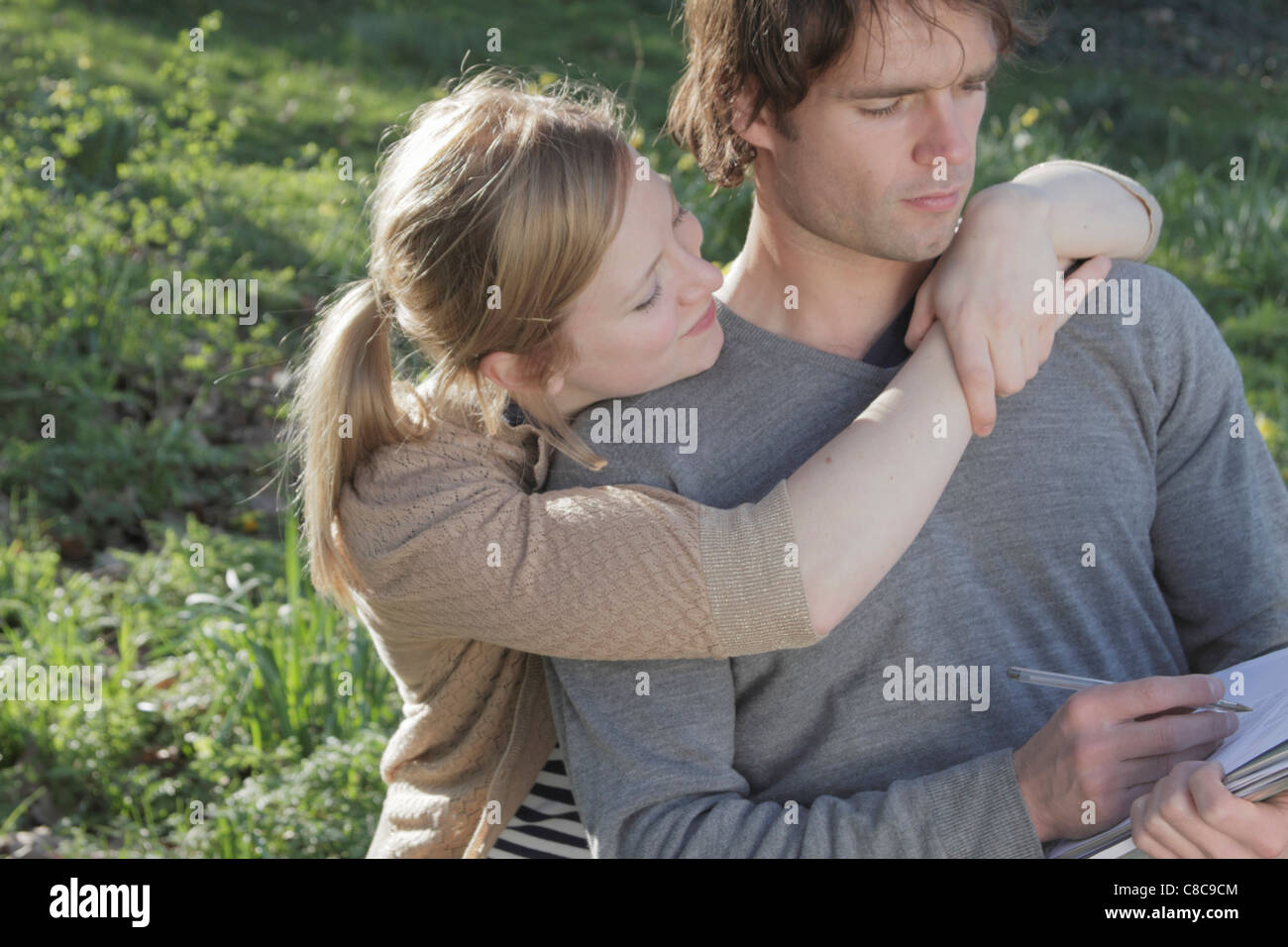 Woman hugging writing boyfriend Stock Photo