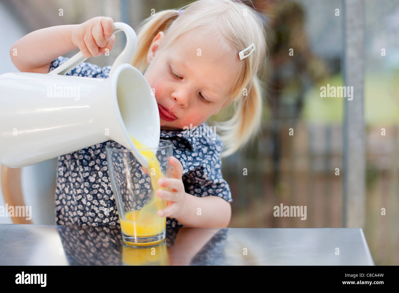 Toddler girl pouring glass of juice Stock Photo Alamy