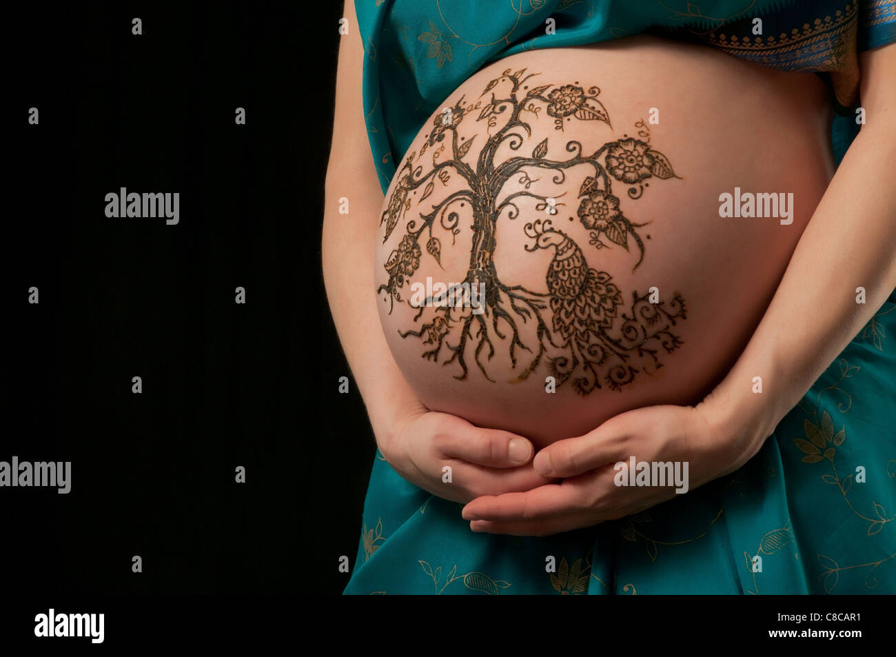 A color photo of a henna 'tree of life' design on a woman's pregnant belly. Stock Photo