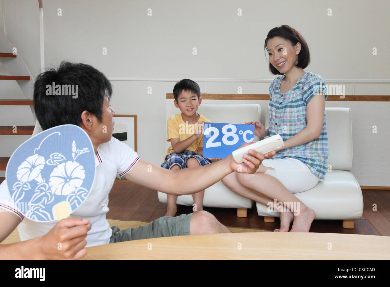 Mother and son cautioning father to save electricity by temperature of air conditioner Stock Photo