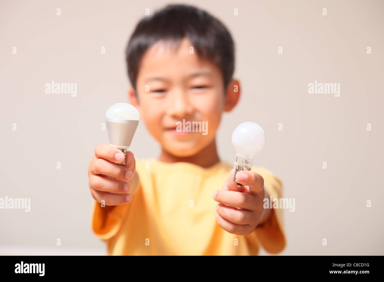 Boy showing light bulb and LED bulb Stock Photo