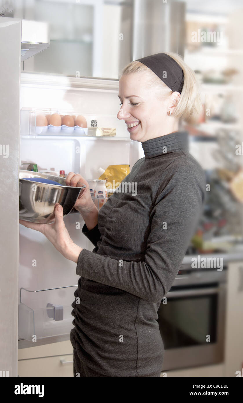 Woman pulling bowl from fridge Stock Photo