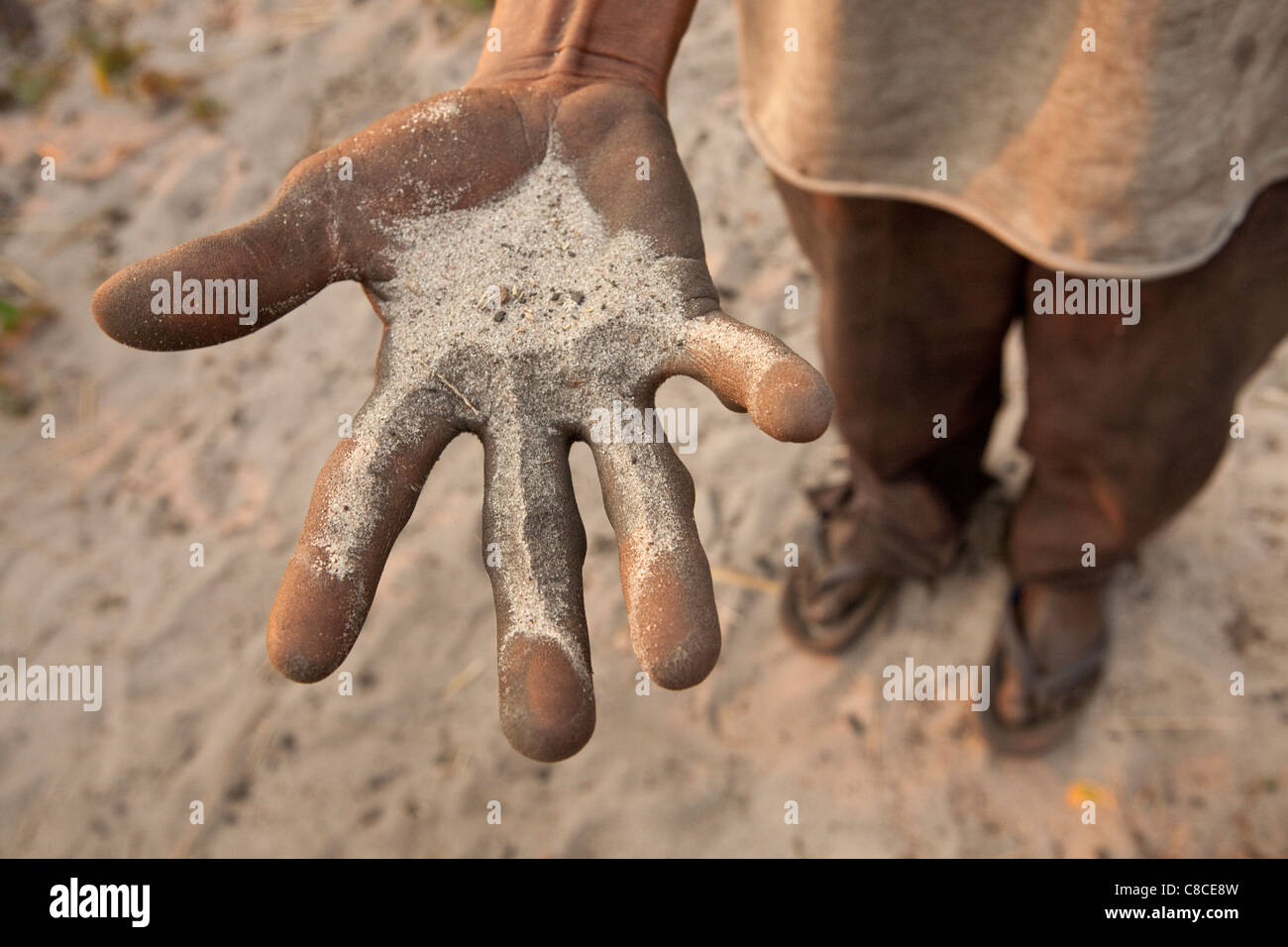 A man demonstrates the sandy soil quality found in Mongu, Zambia, Southern Africa. Stock Photo