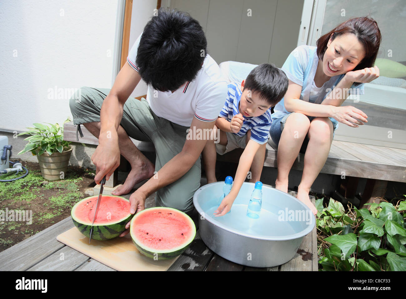 Father cutting watermelon at verandah Stock Photo