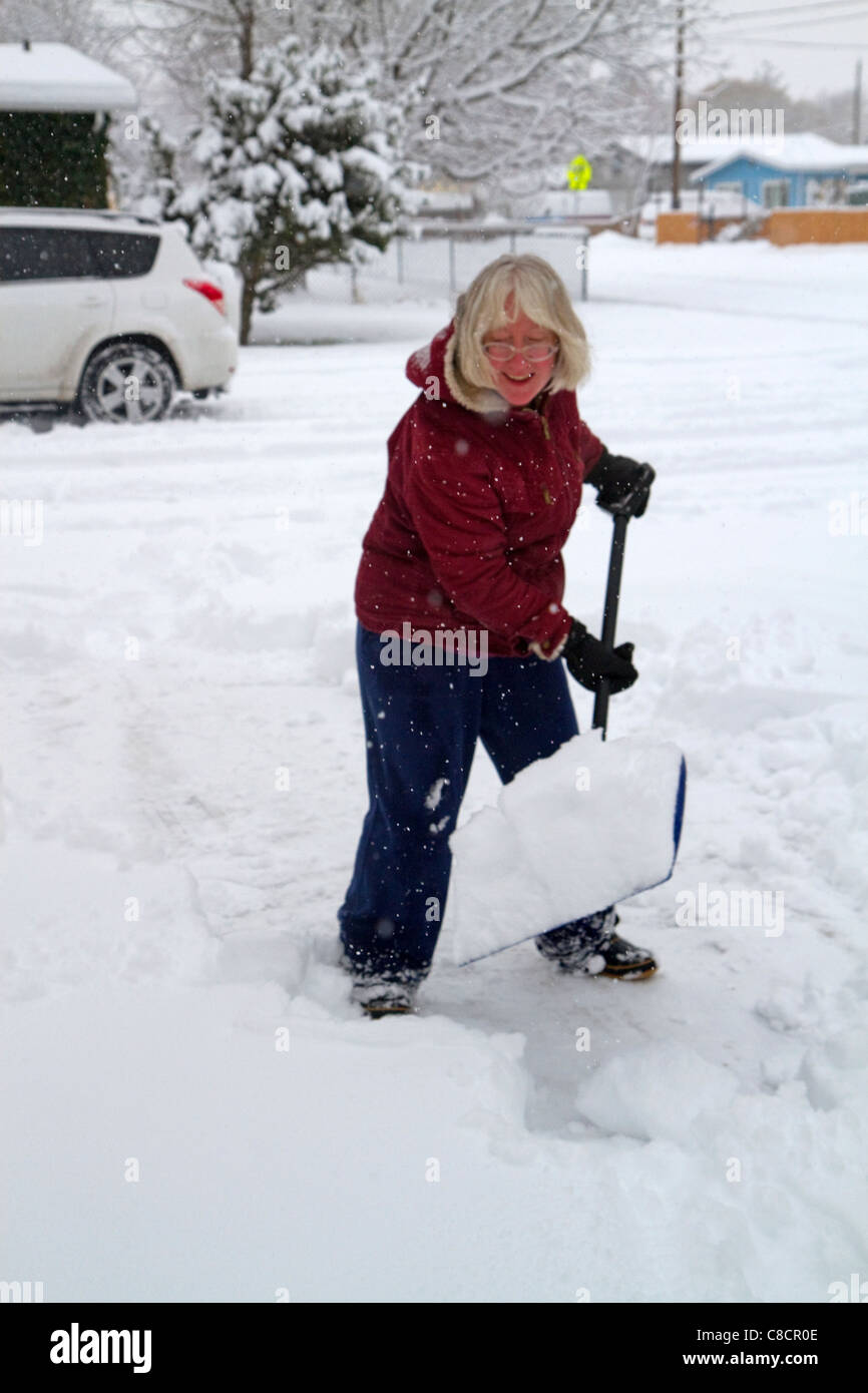 Woman shoveling winter snow off of a sidewalk in Boise, Idaho, USA. Stock Photo