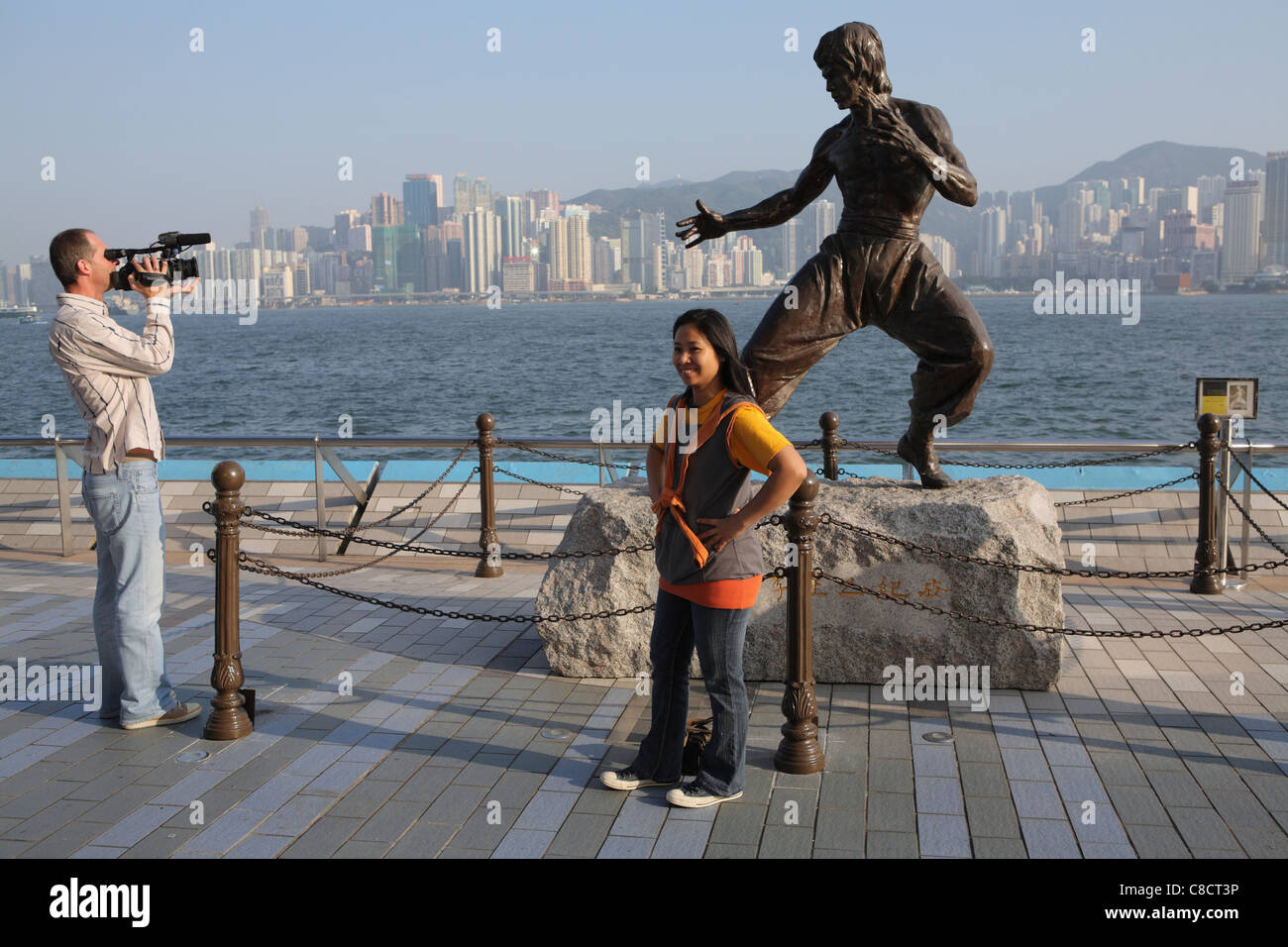 A tourist poses in front of the statue of Hong Kong martial arts and film star Bruce Lee (1940-73) on the Avenue of the Stars Stock Photo
