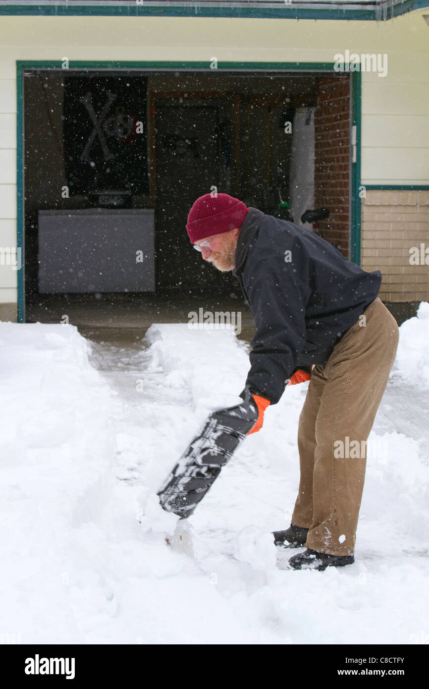 Man shoveling winter snow of off a driveway in Boise, Idaho, USA. Stock Photo
