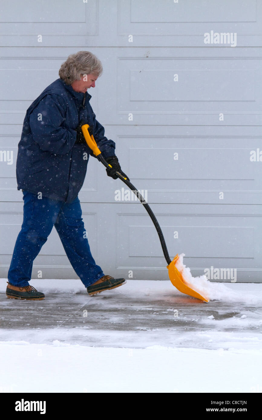 Woman shoveling winter snow of off a driveway in Boise, Idaho, USA. Stock Photo