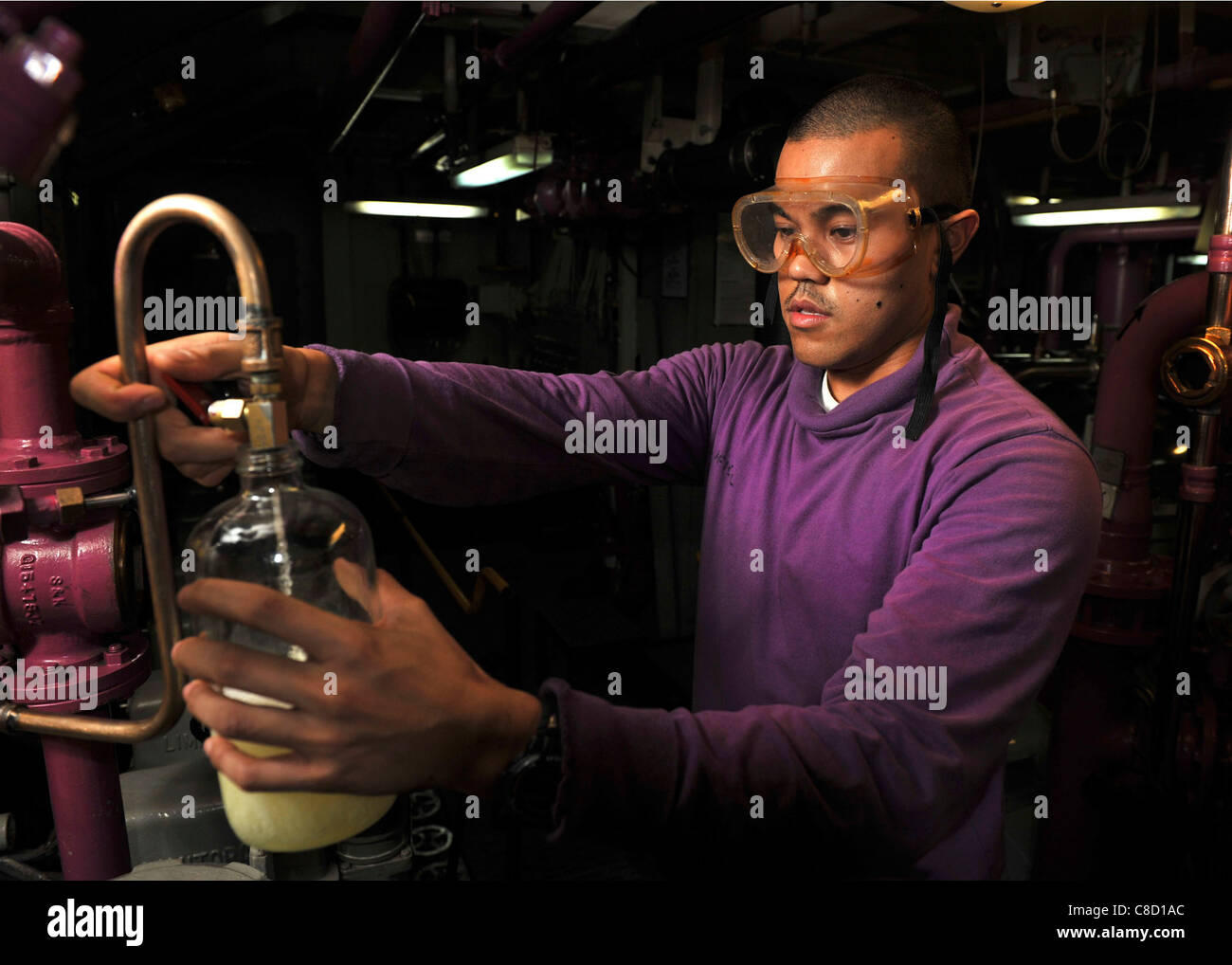 Aviation Boatswain's Mate (Fuel) gathers a sample of fuel to test for