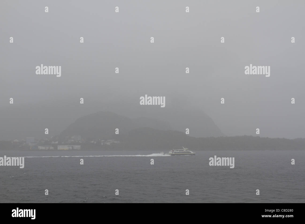 Very foggy and gray day on the seaside in Norway, view of coast, shot from ship, very low visibility Stock Photo