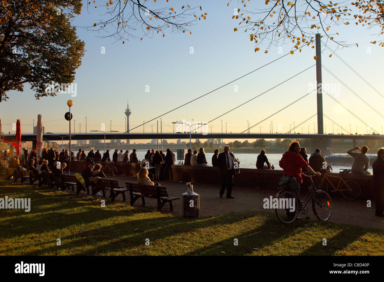 River promenade along Rhine river. People sitting and walking along the riverbanks, old town of Düsseldorf, Germany. Stock Photo