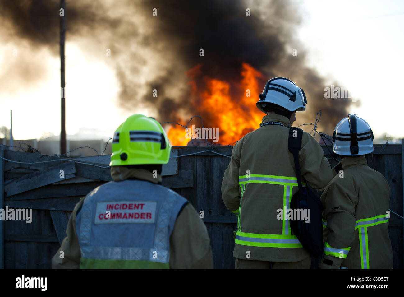 Three senior fire officers assess the extent of a fire that has been started on the Dale Farm traveller site during the eviction Stock Photo