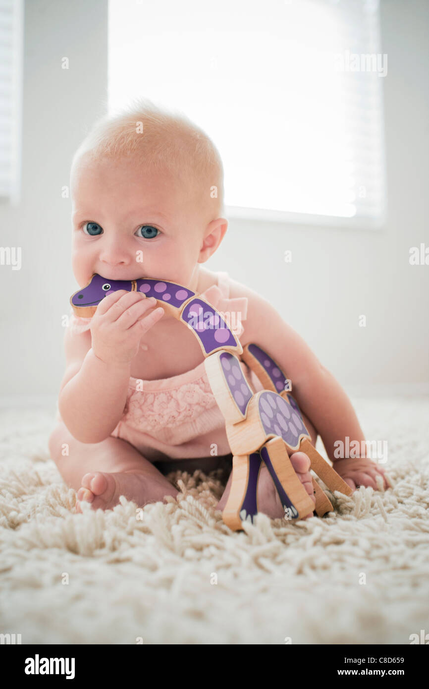 Baby Girl Teething on Wooden Toy Stock Photo