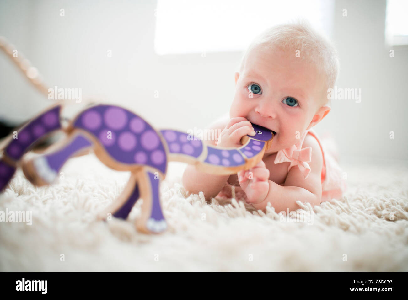 Baby Girl Teething on Wooden Toy Stock Photo