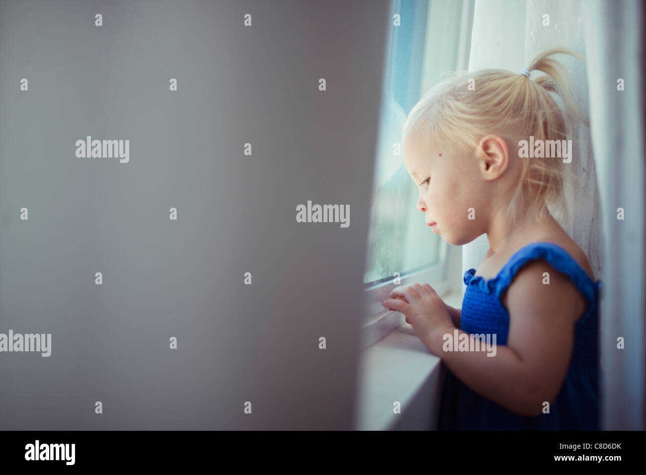 Toddler Girl looking out Window Stock Photo