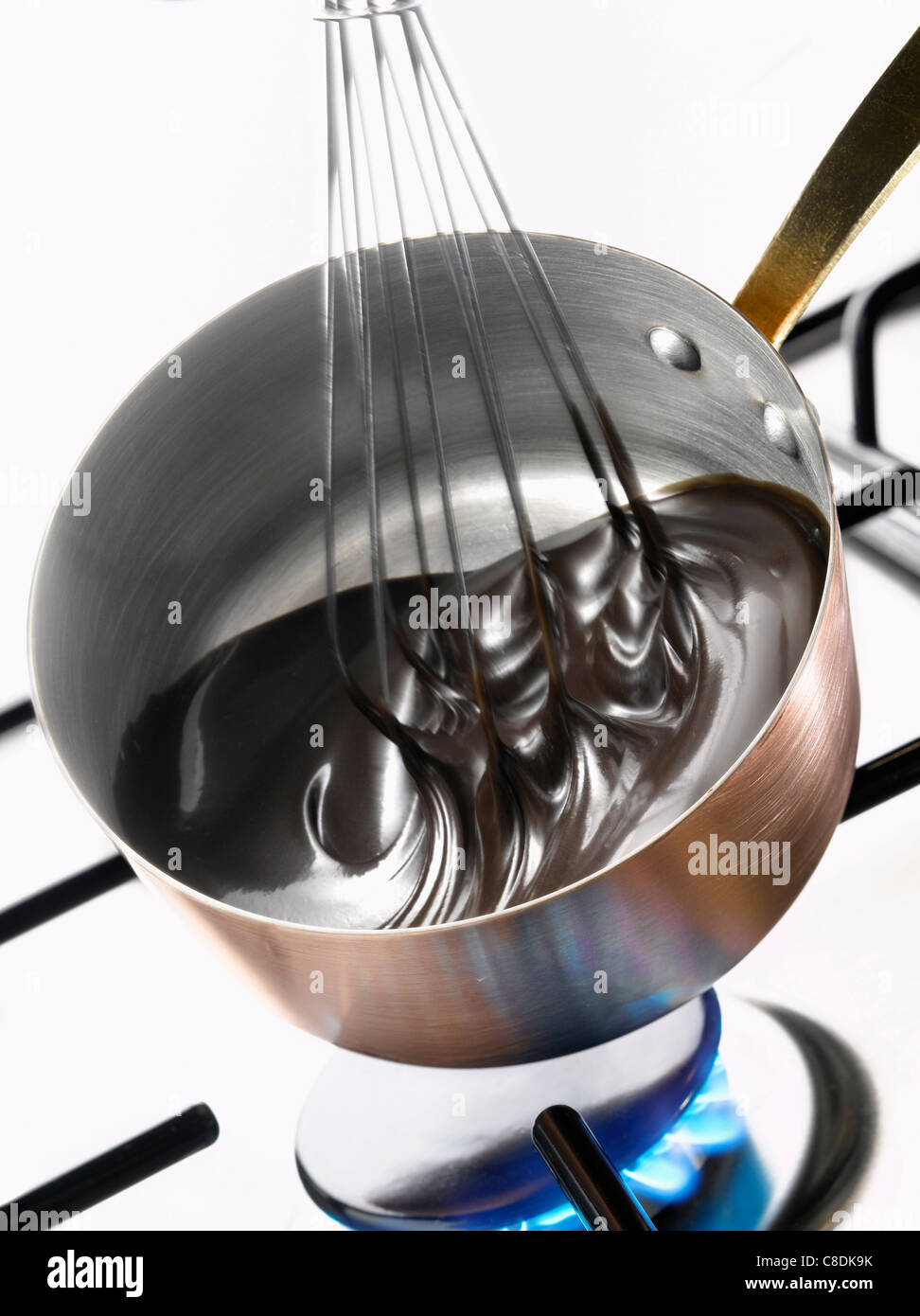 Whipping the melted chocolate in the copper saucepan Stock Photo Alamy
