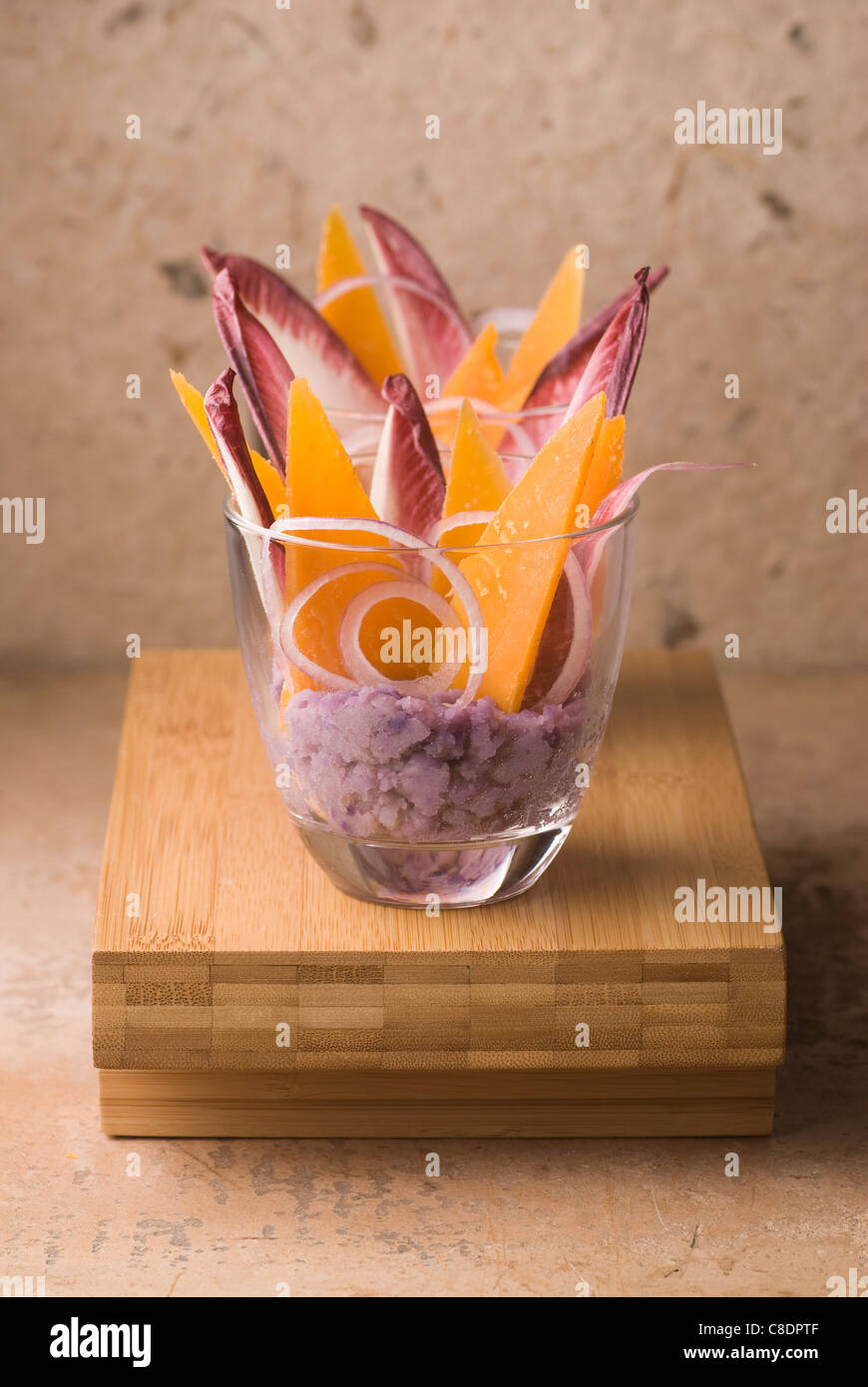 Cream of Vitelotte potatoes with red chicory leaves and thin slices of Mimolette Stock Photo