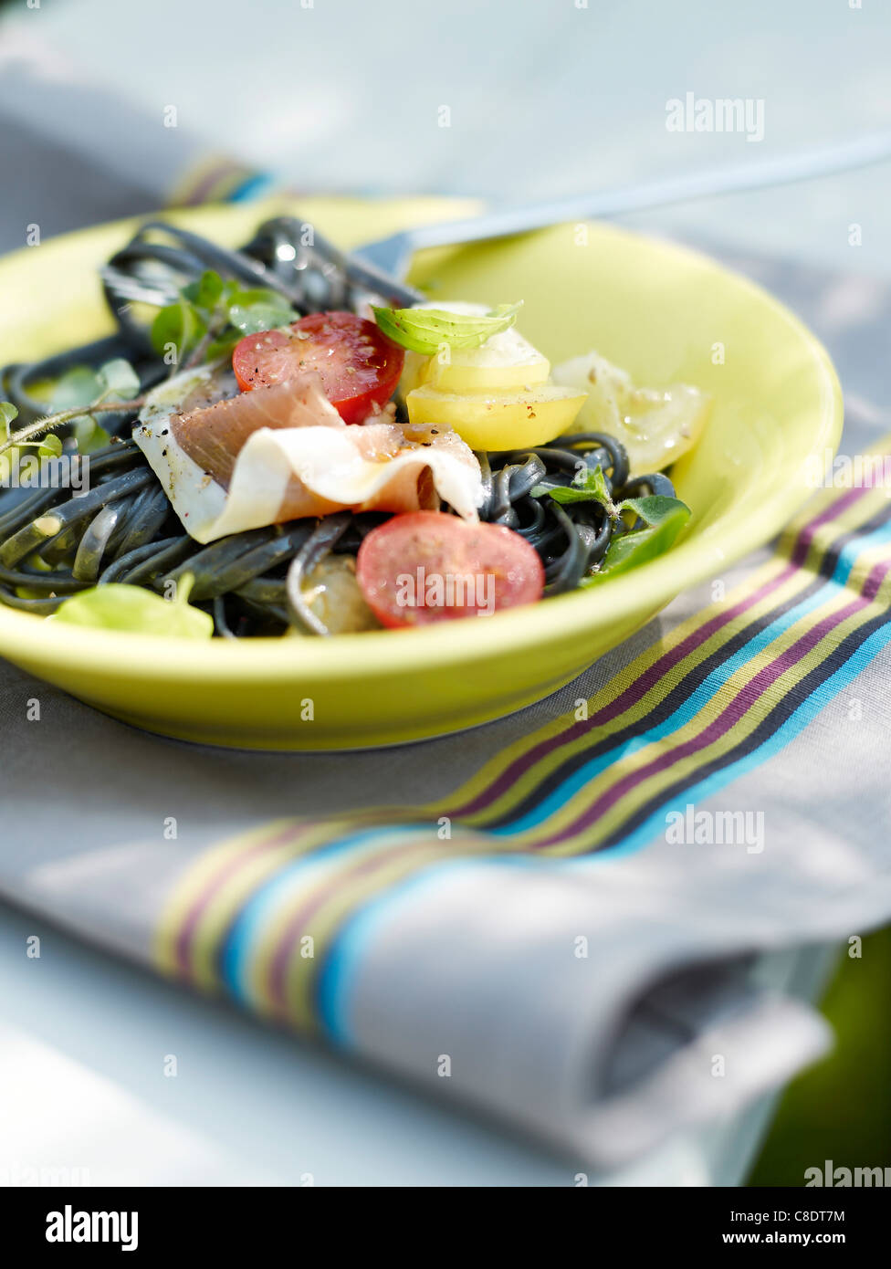 Squid ink linguinis with two types of tomatoes and raw ham Stock Photo