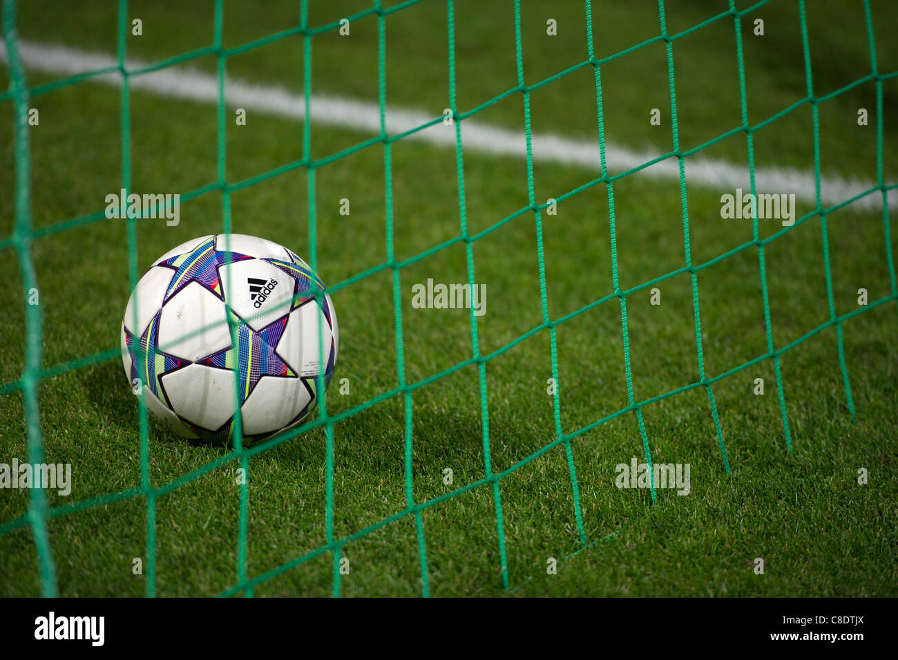 Adidas Champions League ball in the goal net and over the white line Stock Photo