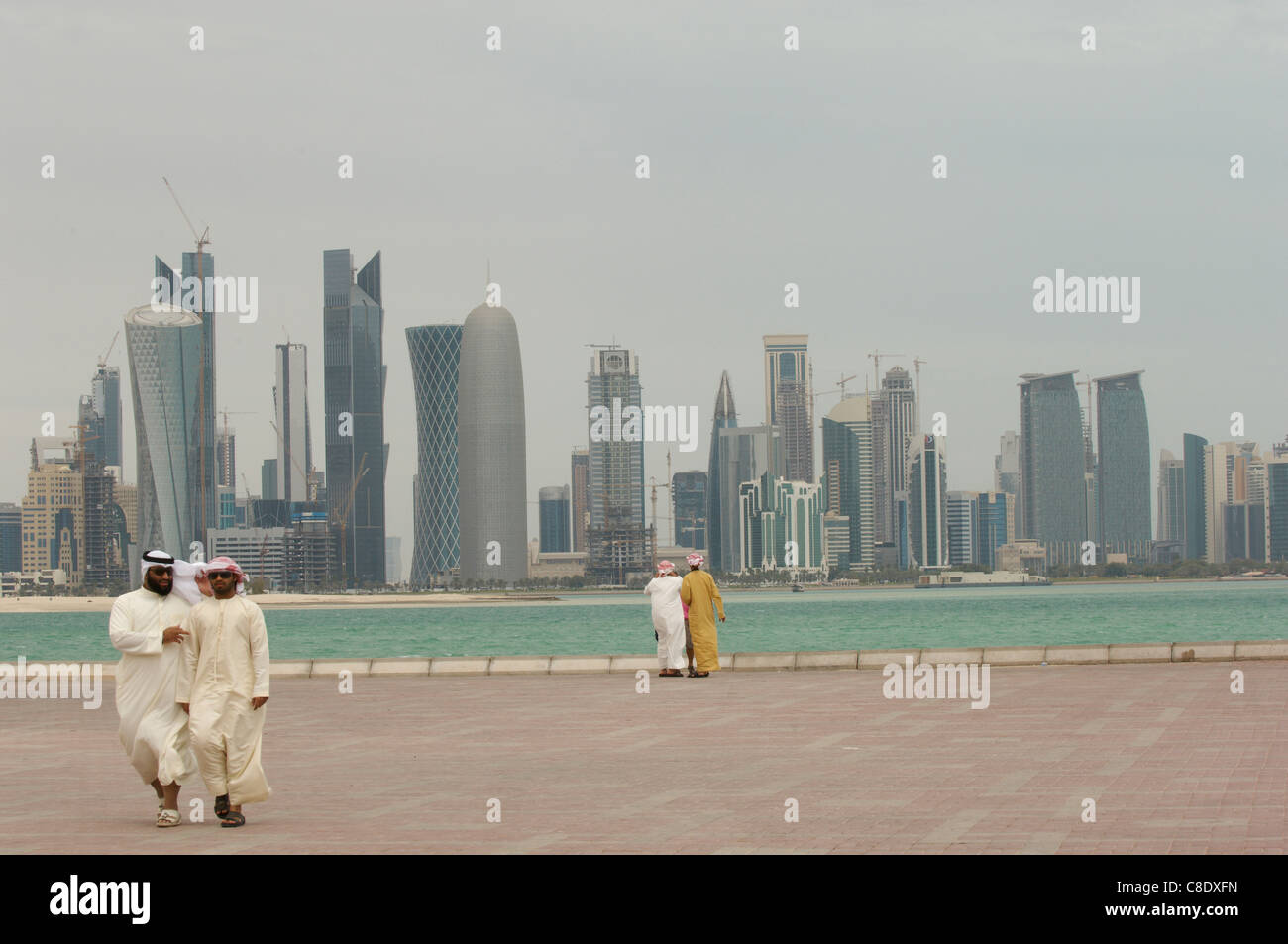 middle eastern men looking at doha city center skyline from corniche qatar Stock Photo