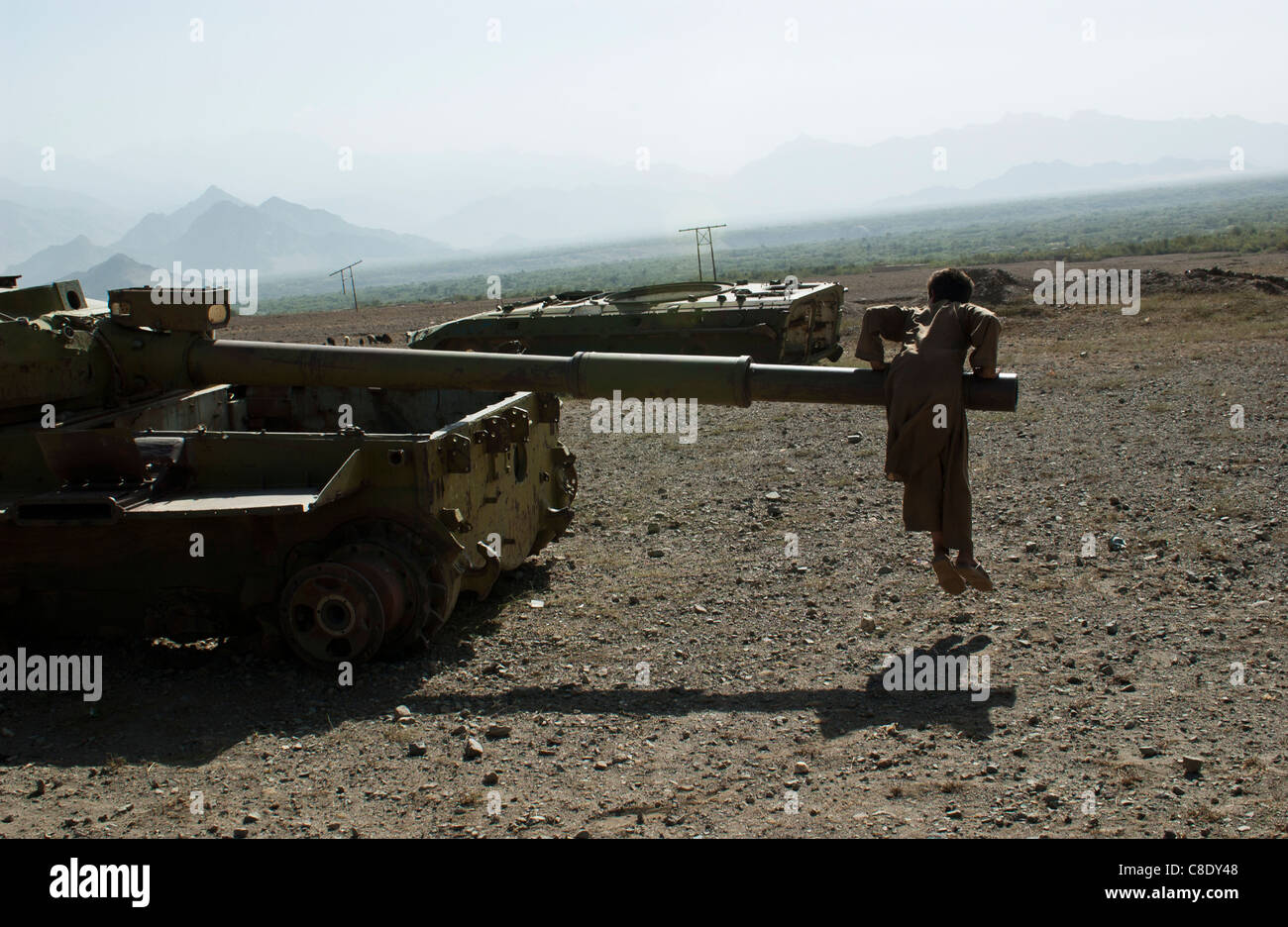 A child plays on an abandoned Soviet era tank outside Tawakh, near the Panjshir Valley, Afghanistan, October 2004. Stock Photo