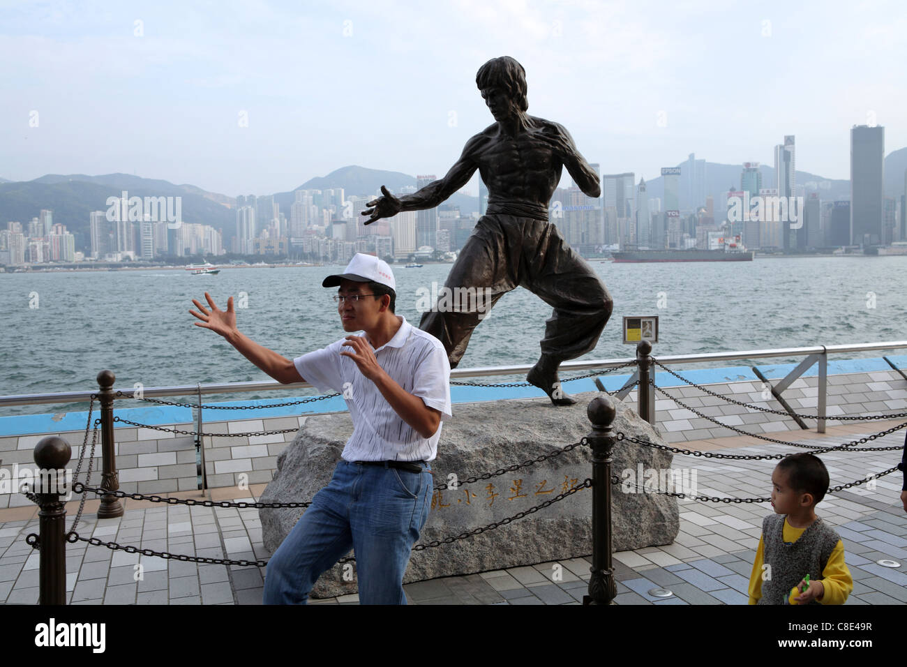 A tourist poses for photograph by statue of Hong Kong martial arts and