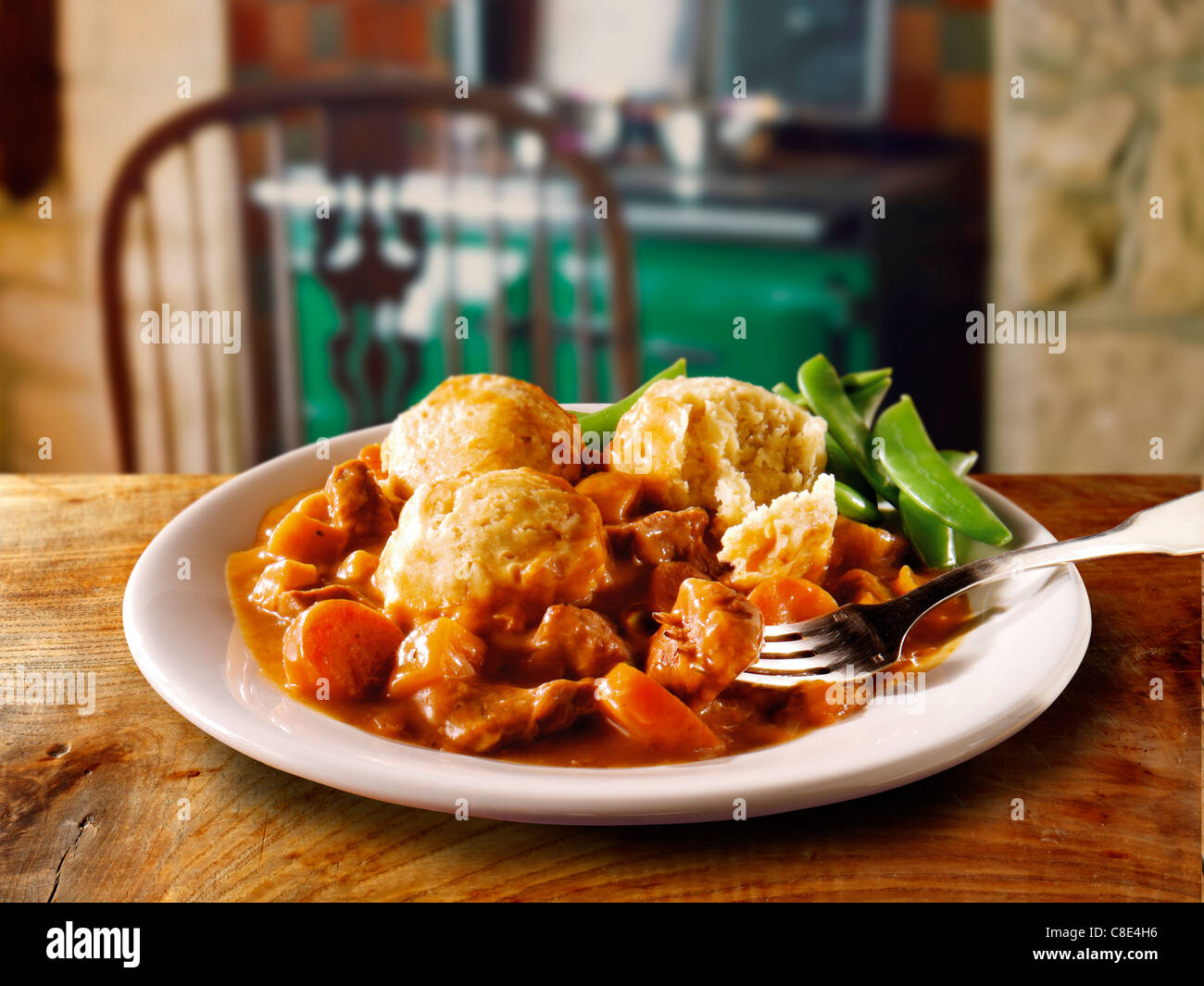 Traditional British cooked Beef Stew nd Dumplins on a white plate in a traditional kitchen setting ready to eat Stock Photo