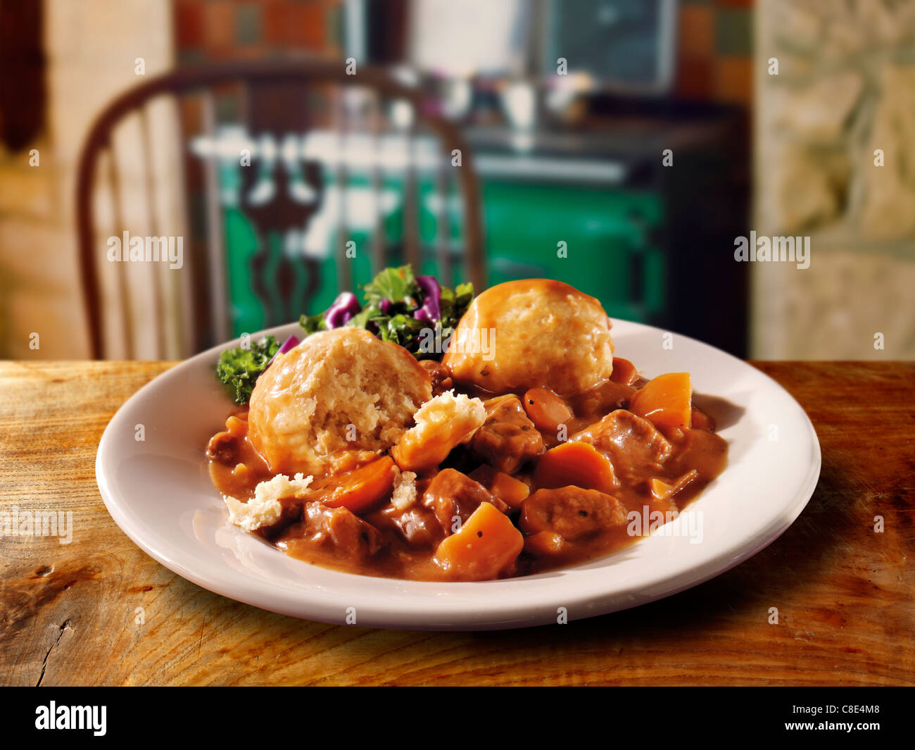 Traditional British cooked Beef Stew nd Dumplins on a white plate in a traditional kitchen setting ready to eat Stock Photo