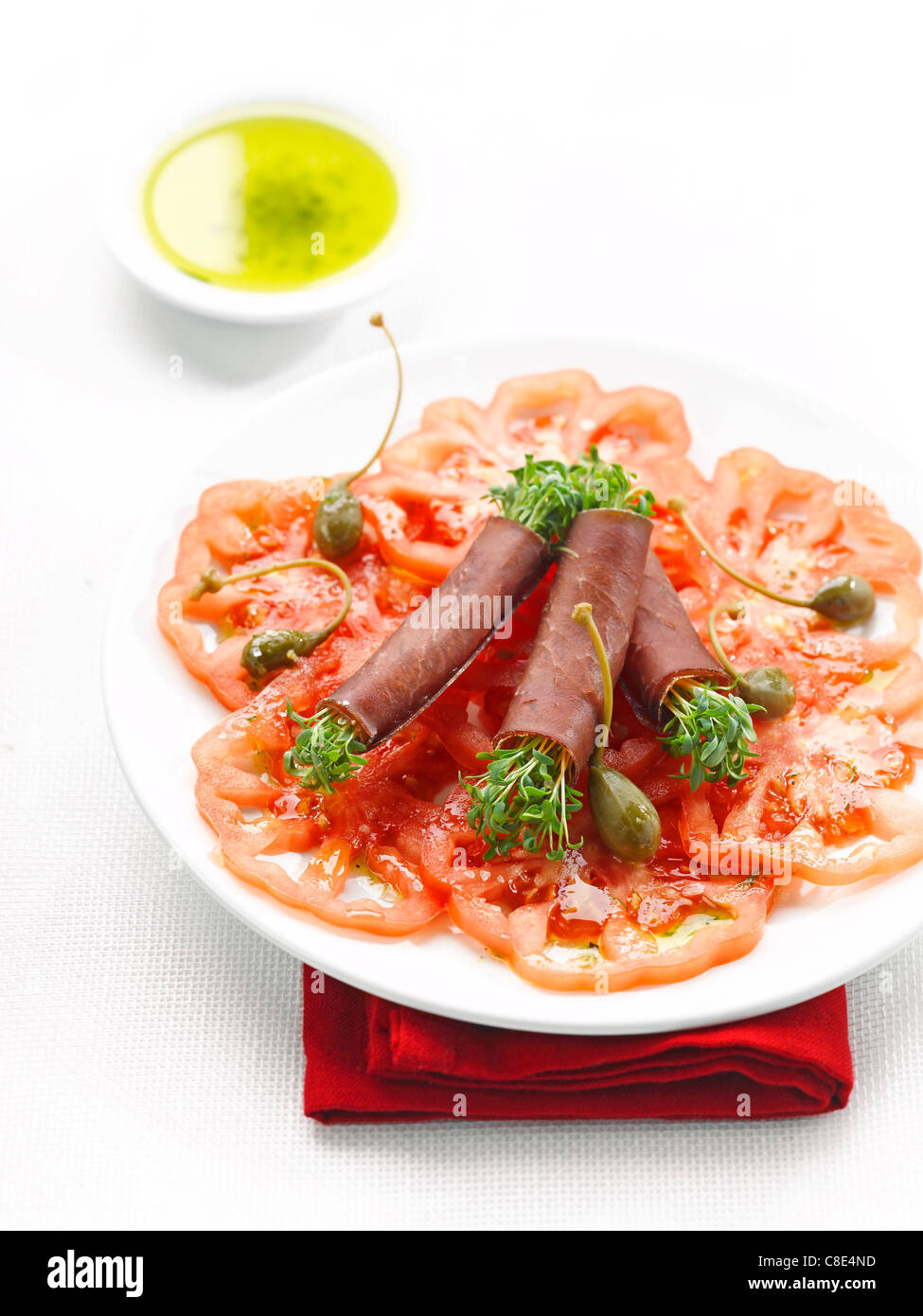 Coeur de boeuf tomato carpaccio and grisons meat rolls filled with capers  Stock Photo - Alamy