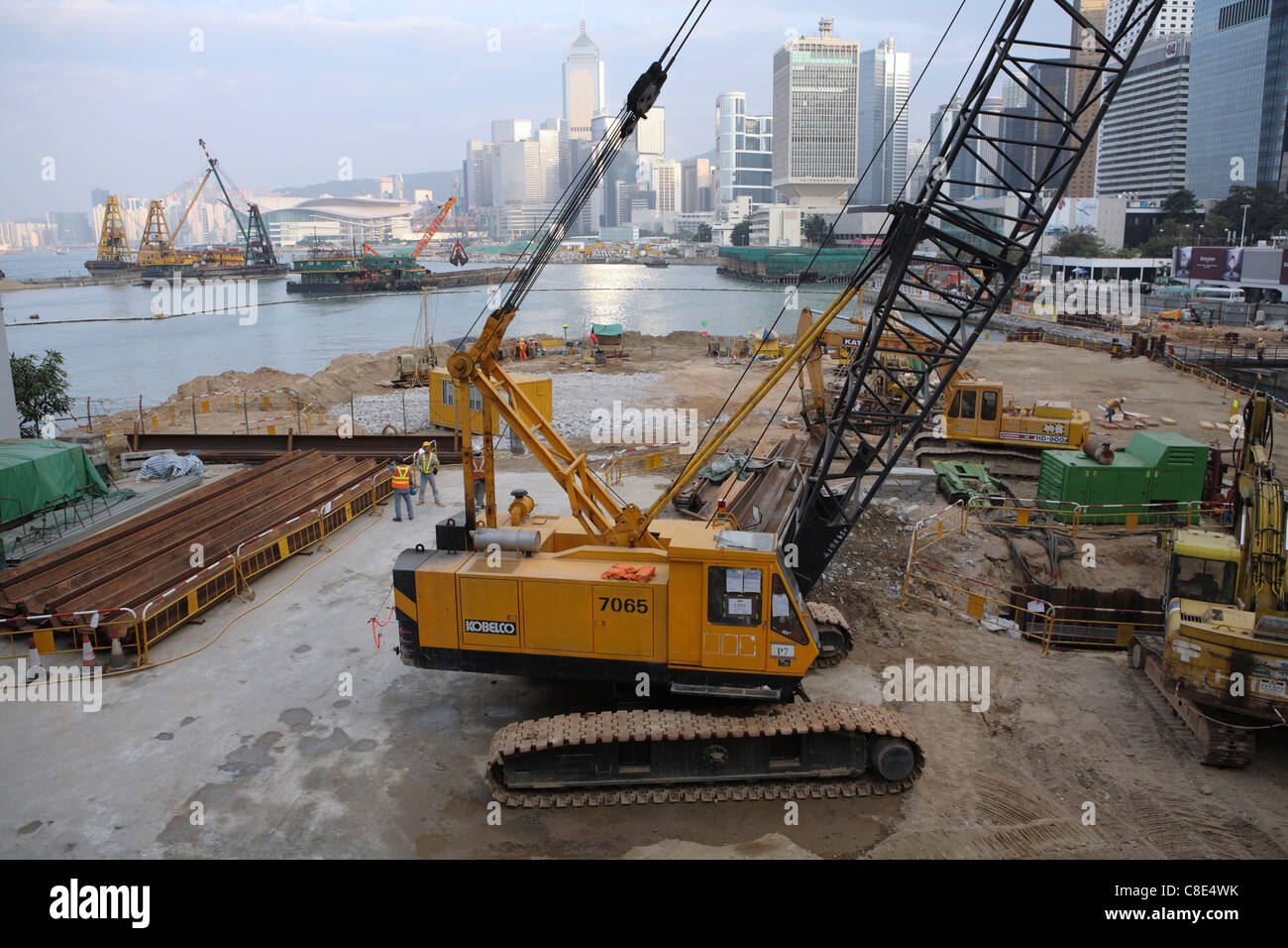 huge yellow crane working to reclaim real estate land in Hong Kong's Victoria Harbor China, view across harbor to Kowloon Stock Photo