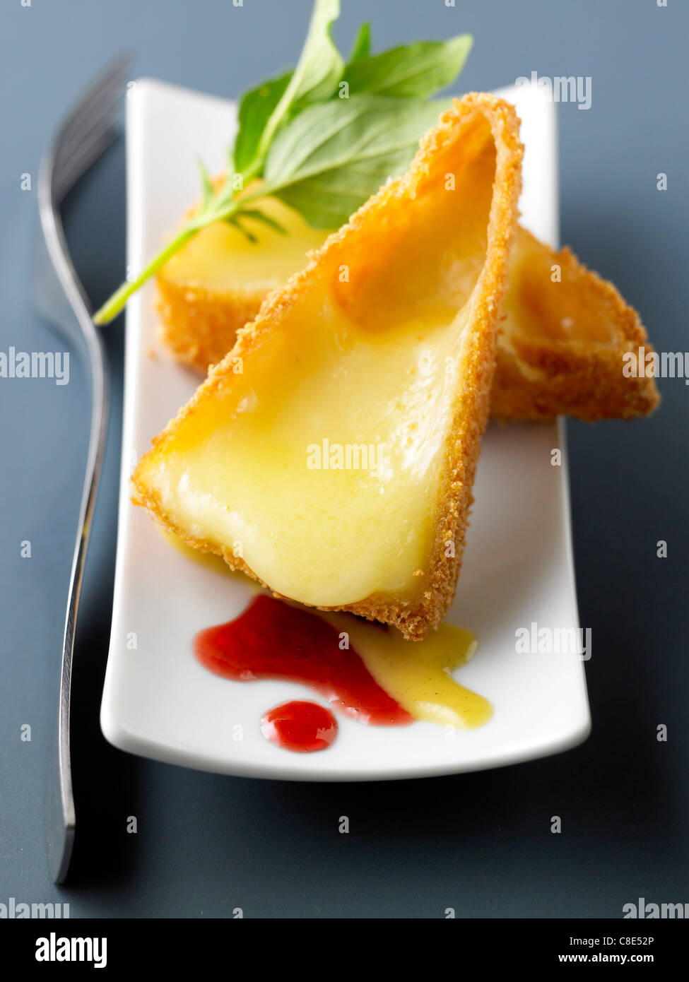 Hot Brie coated with breadcrumbs,with redcurrant sauce and honey sauce Stock Photo