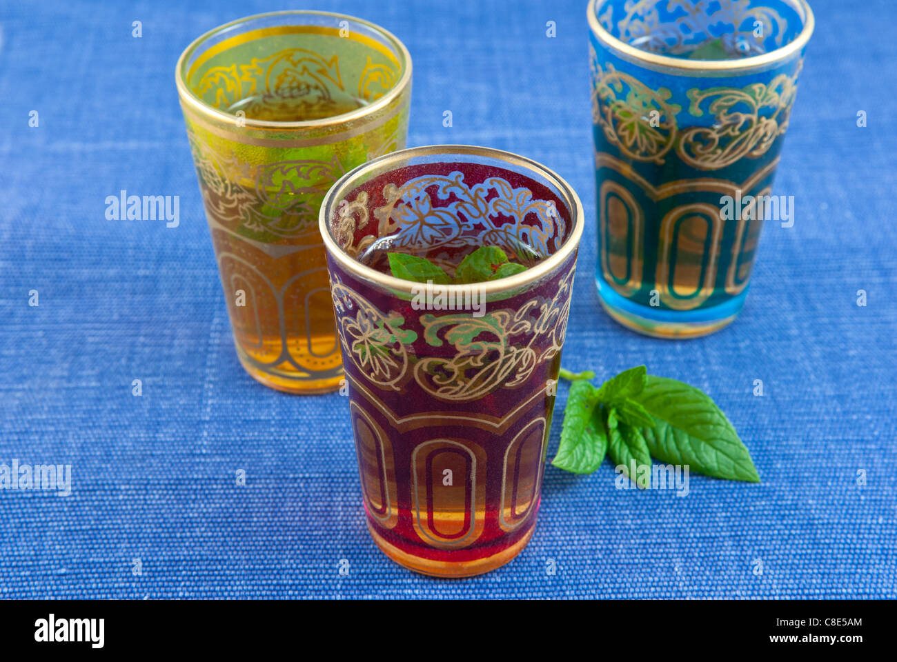 Small coloured glasses of mint tea on a blue background . Stock Photo