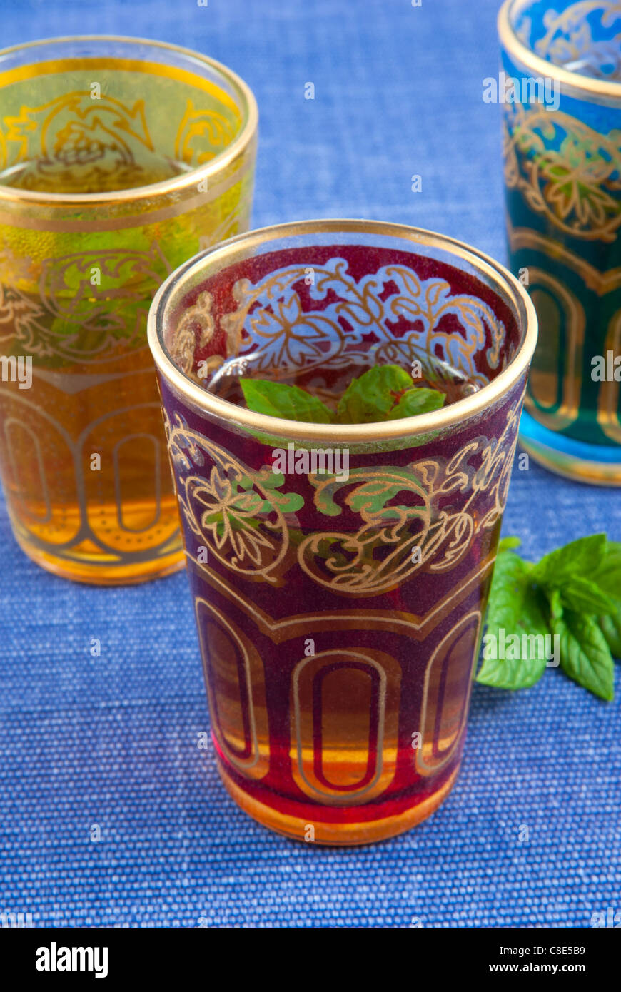 Small coloured glasses of mint tea on a blue background . Stock Photo