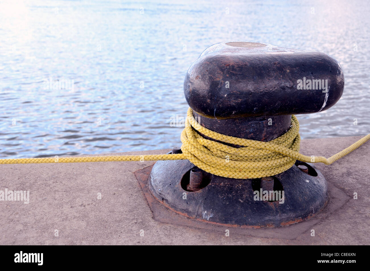 Thick rope rotated around mooring pole berth. Stock Photo