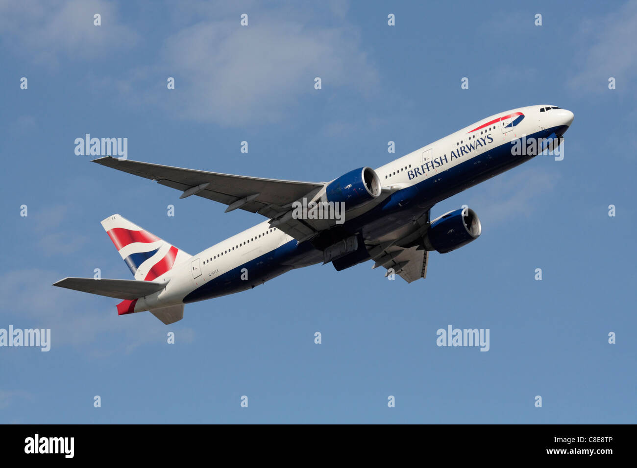 British Airways Boeing 777-200ER widebody passenger jet climbing on departure against a blue sky Stock Photo