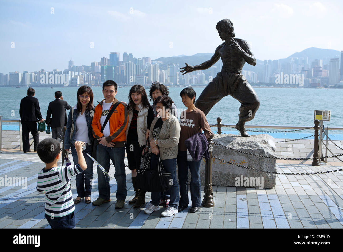 Tourists pose for photographs by statue of Hong Kong martial arts and