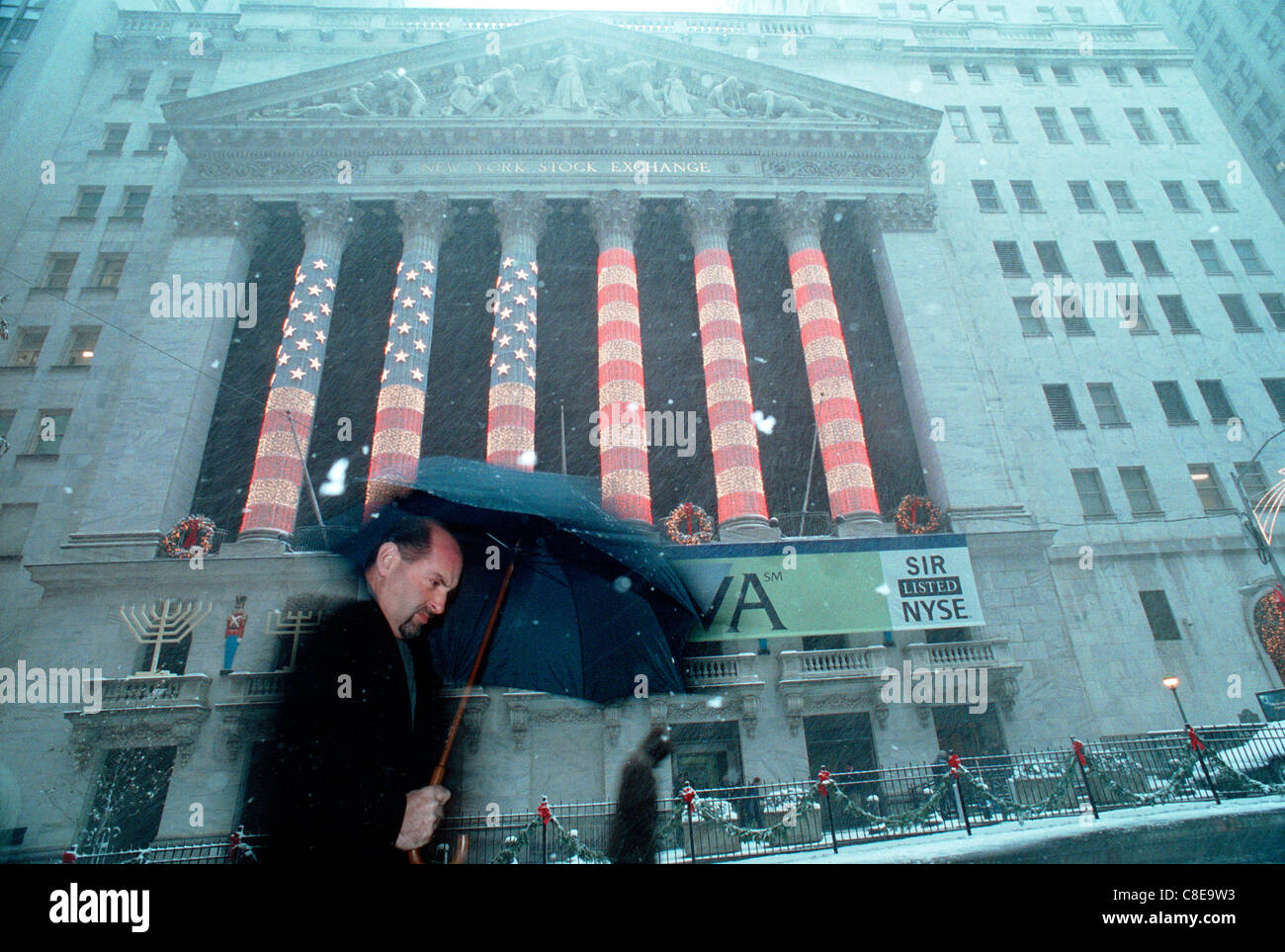 Wall Street workers and visitors pass the New York Stock Exchange, decorated for Christmas in the snow Stock Photo