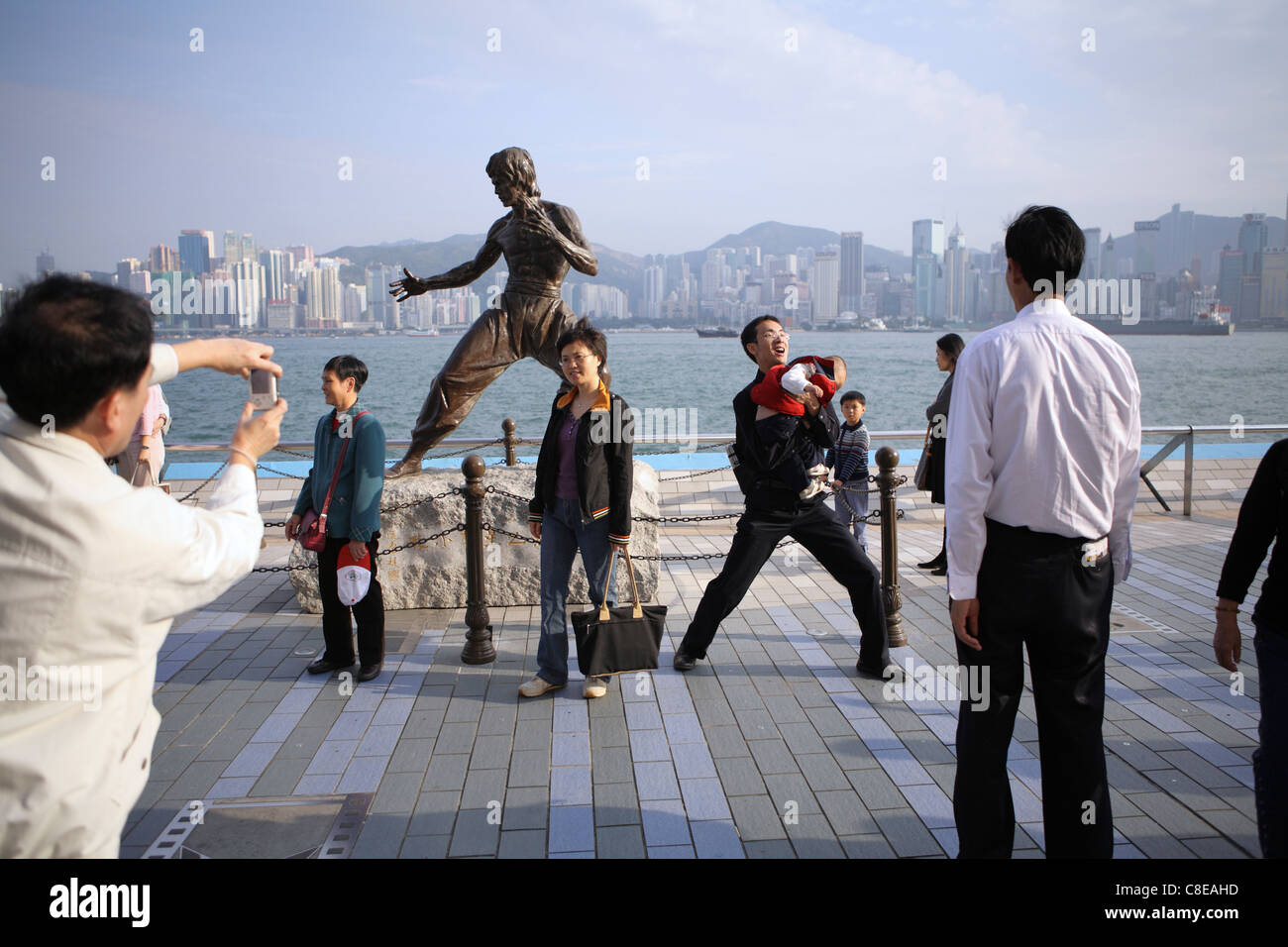 Tourists pose for photographs by statue of Hong Kong martial arts and