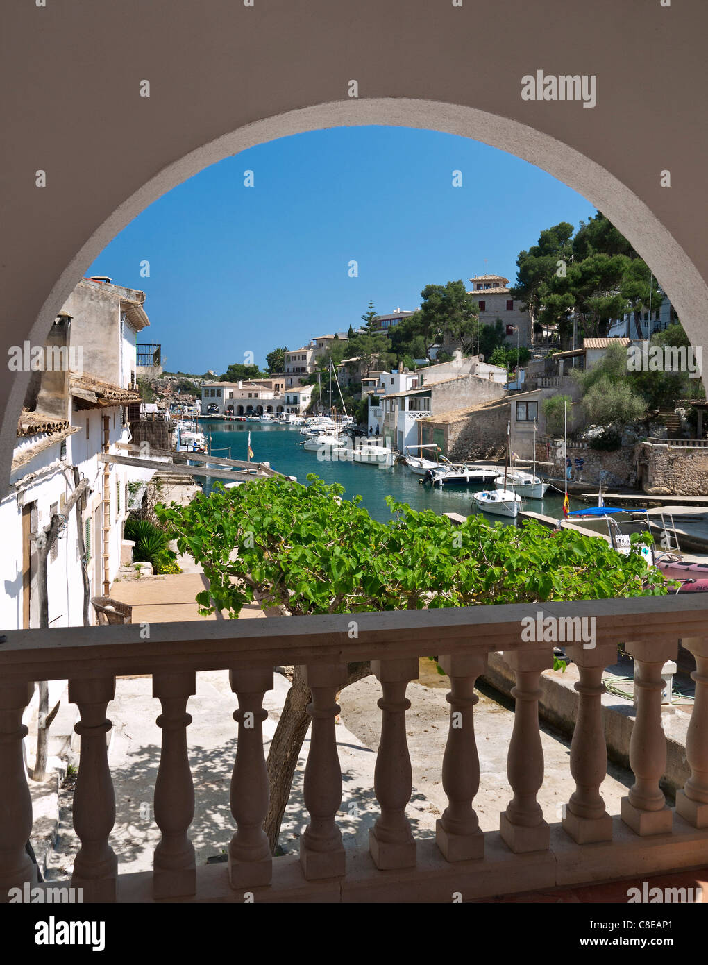 Cala Figuera harbour view framed by vacation villa arch with fishing boats houses and villas, Mallorca Balearic Islands Spain Stock Photo