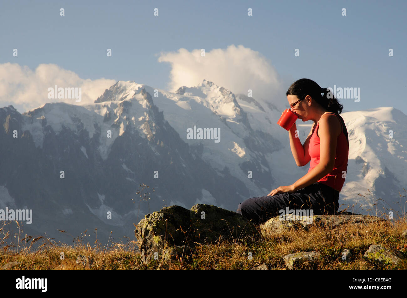 A young woman drinking tea on wild camp in the French Alps Stock Photo
