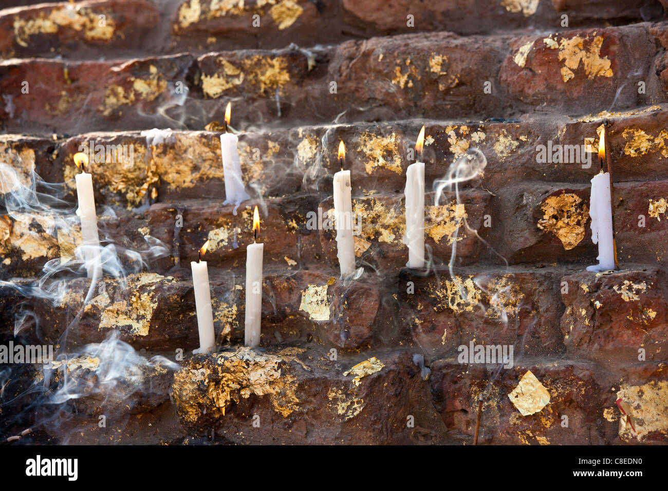 Lighted candles and gold leaf offering Buddhist prayers at Dharmarajika