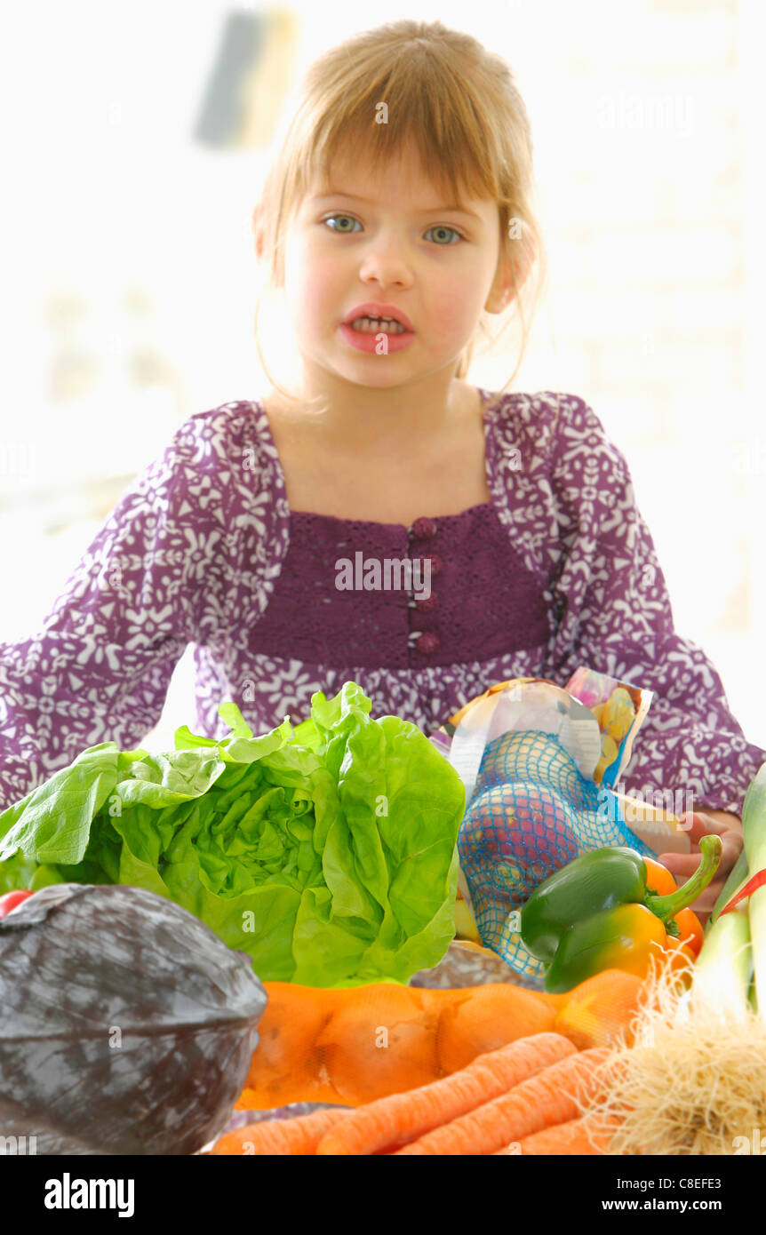 Young girl infront of a table of vegetables Stock Photo