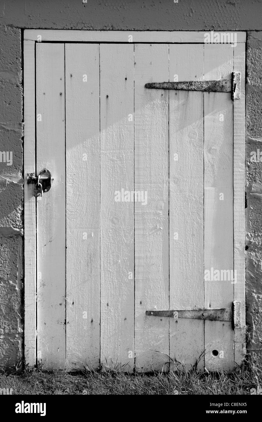 The locked wooden door of a small brick outbuilding. Stock Photo