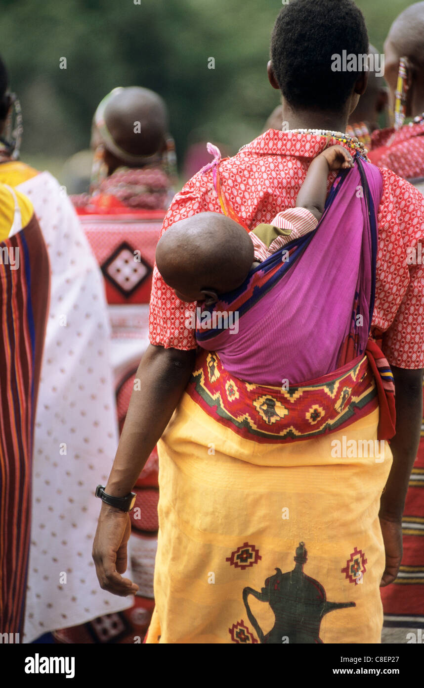 Lolgorian, Kenya. Siria Maasai Manyatta; woman with baby slung in a cotton wrap cloth on her back. Stock Photo